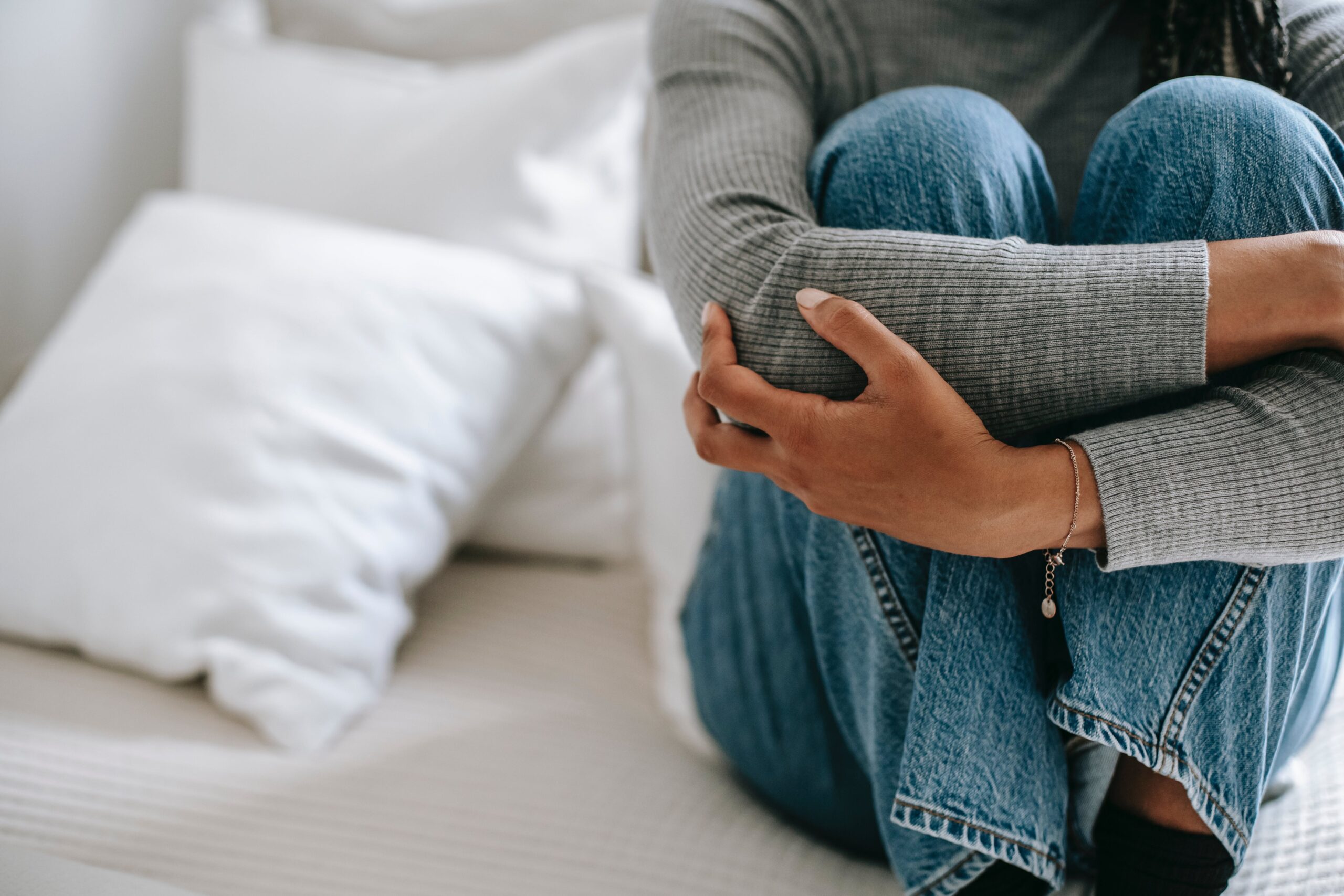 Woman on bed with arms around legs